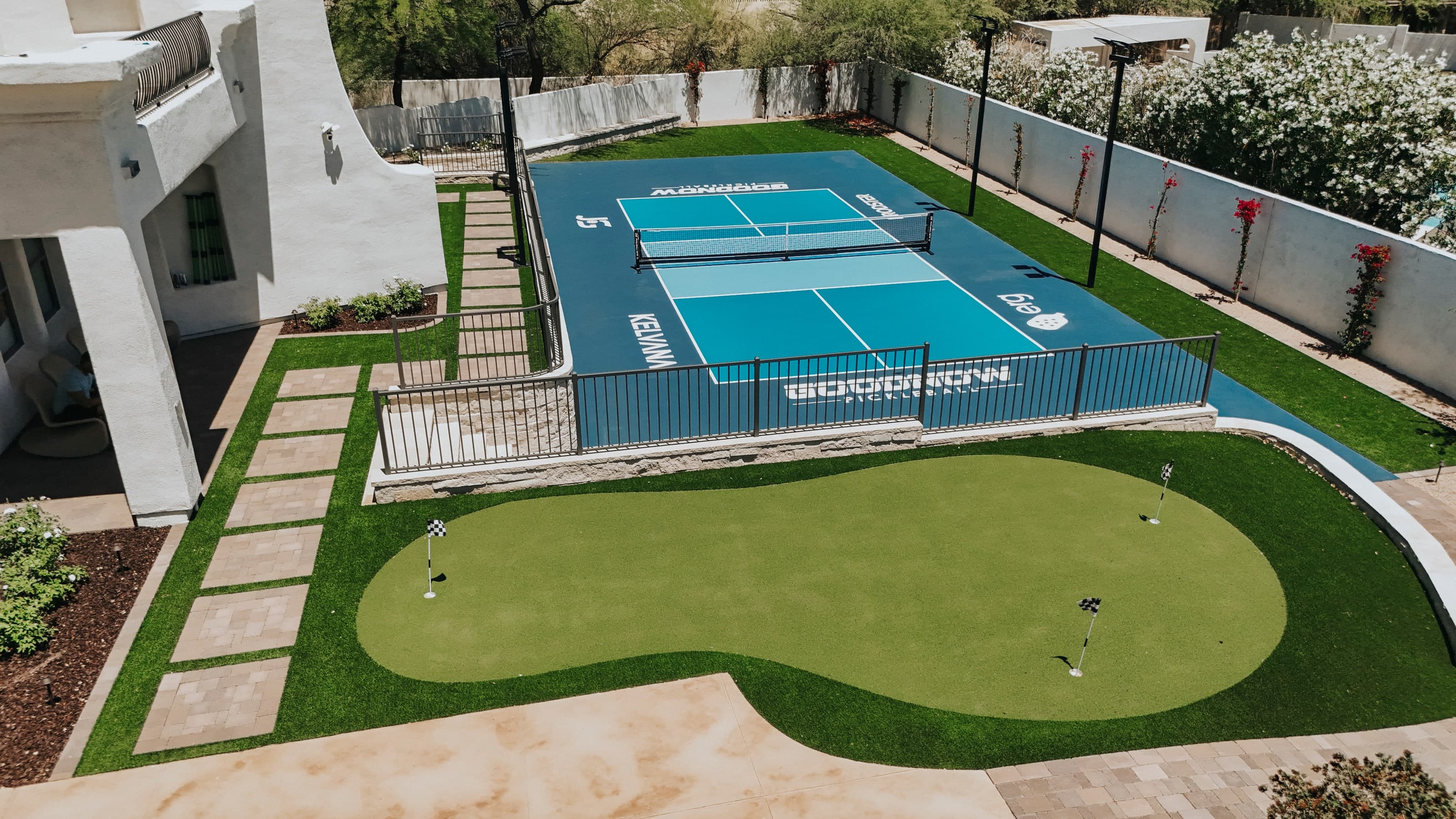 Aerial view of a backyard pickleball court and putting green beside an Arcadia home
